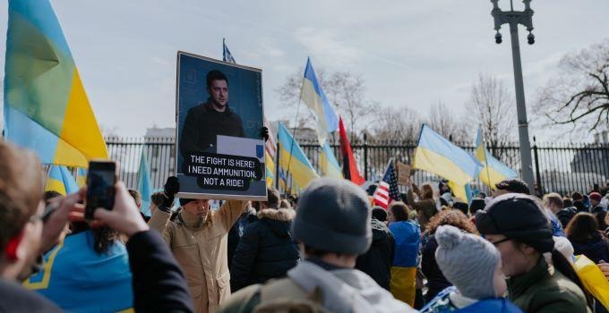 People demonstrating against the war in Ukraine where one person is holding a poster with the image of Zelensky.  