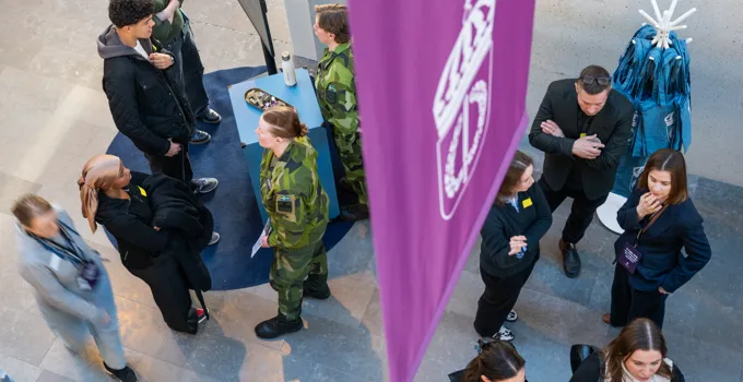 En grupp människor som står runt en lila flagga.