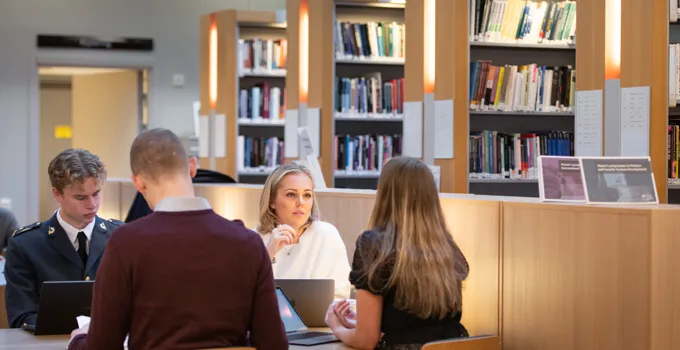 En grupp människor som sitter vid ett bord i ett bibliotek.