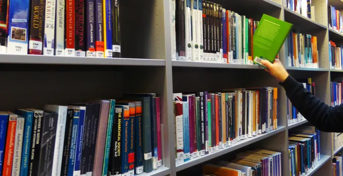 En kvinna läser en bok på ett bibliotek.