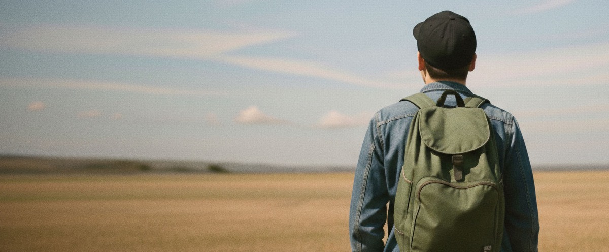 Man med rygg mot kamera tittar ut över ett fält.