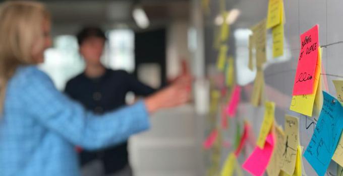 Personer vid en whiteboard med post-it-lappar. 
