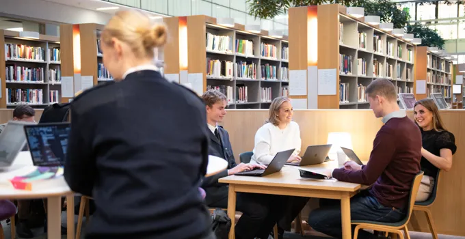 En grupp människor som sitter vid ett bord i ett bibliotek.
