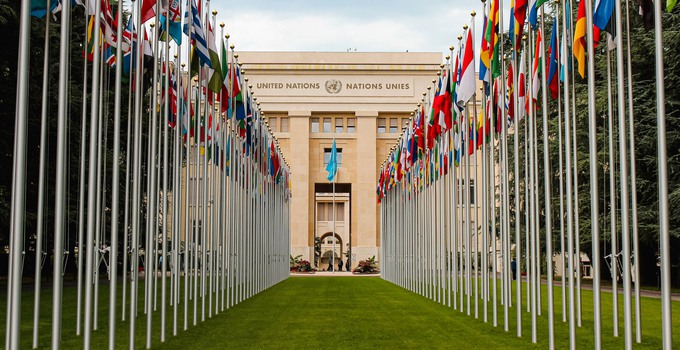 FN-byggnaden i Gèneve med flaggor framför. 