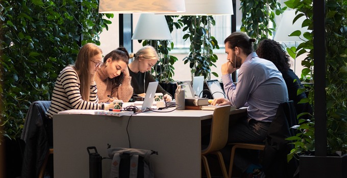 Studenter pluggar gemensamt vid bord.