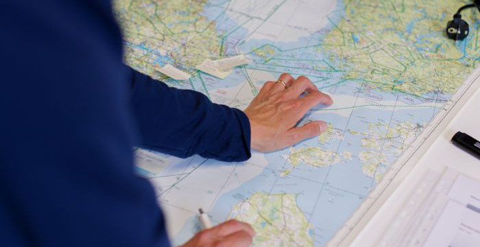 Persons arm som pekar på en karta. 