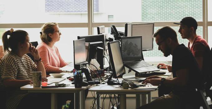 Fyra personer vid datorskärmar på ett kontor.