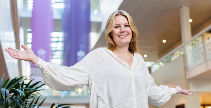 Emma Nilsson slår ut med armarna i Försvarshögskolans entré.