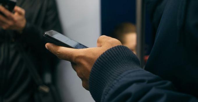 Hand som håller en mobiltelefon.