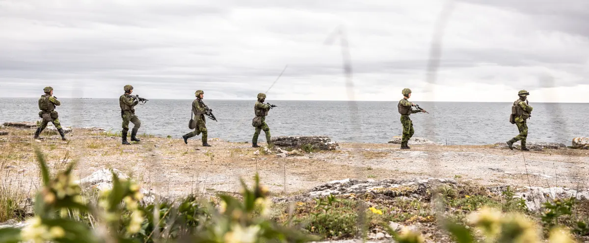 En grupp soldater som går över ett fält intill havet.