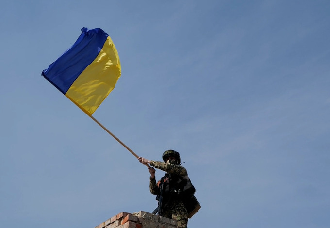 Ukrainska flaggan i händerna på en soldat.