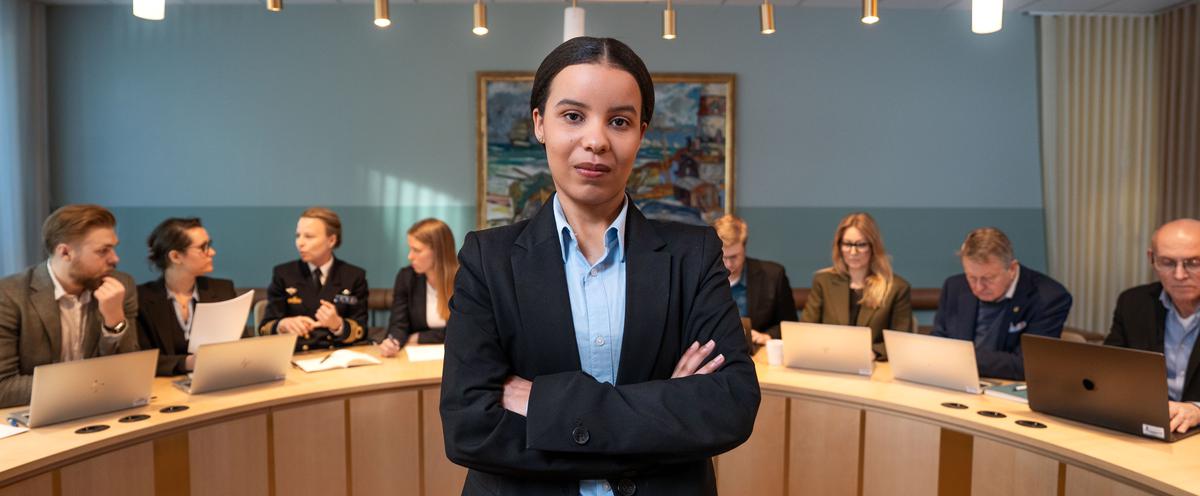 Student i mötesrum framför en panel av deltagare.