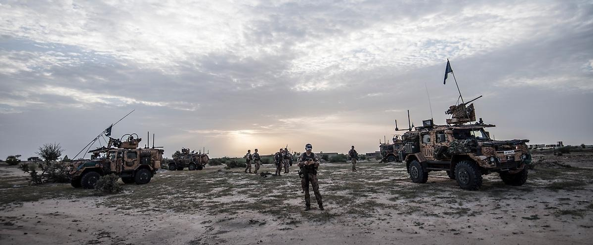 En grupp militärfordon som står parkerade på en grusplan.