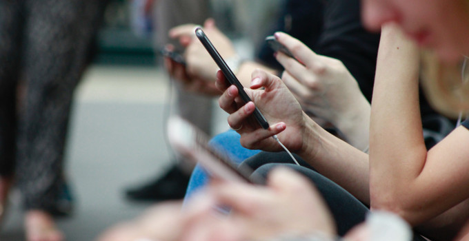 En grupp människor som sitter bredvid varandra och använder mobiltelefoner.