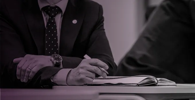 Korslagda armar på ett konferensbord, rosatonad bild.