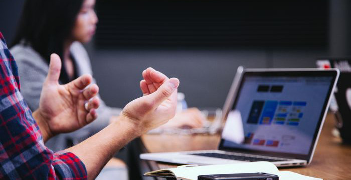 Blurrad bild av kursdeltagare vid bord med laptop.