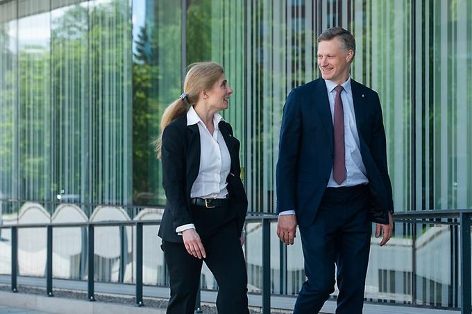 Two persons walking and talking outside the main buildning of the Swedish Defence University 