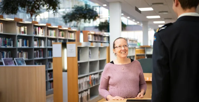 En kvinna som står framför en man i ett bibliotek.