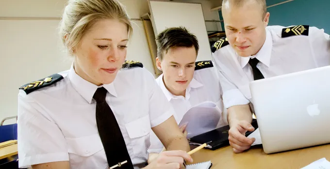 A group of people sitting at a table working on a laptop.