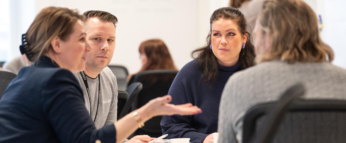 Kursdeltagare i samtal runt ett bord.