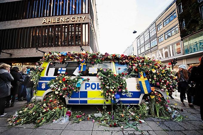 Polisbil täckt av blommor utanför Åhléns city.