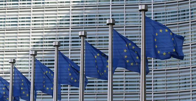 EU-flaggor på rad utanför en kontorsfasad. 