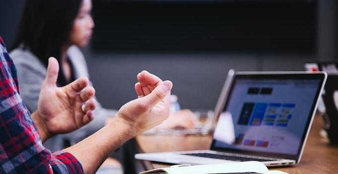 Närbild på händer framför en datorskärm vid ett möte. 