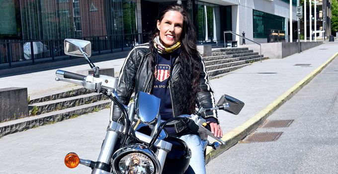Linda Strömberg på motorcykel framför Försvarshögskolan.