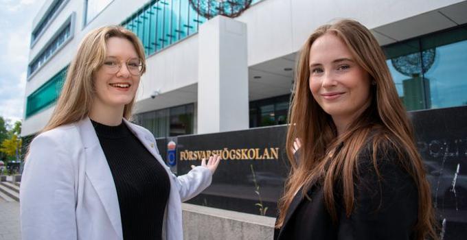 Två studentambassadörer vid Försvarshögskolans byggnad.