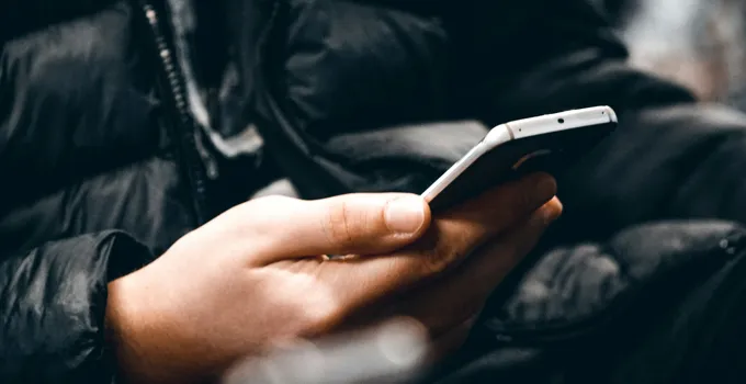 En person som håller en mobiltelefon i handen.