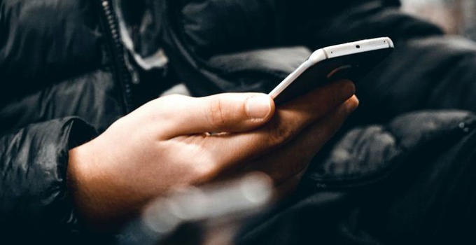 Närbild på hand som håller en mobiltelefon. 