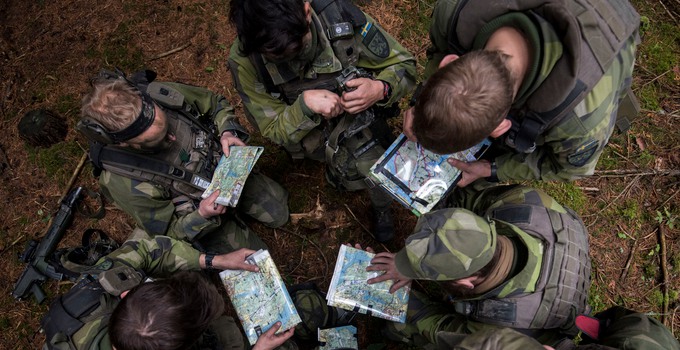 Soldater i en grupp som tittar på kartor. 