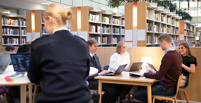 En grupp människor som sitter vid ett bord i ett bibliotek.