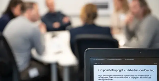 Blurrad bild av kursdeltagare med laptop i förgrunden.