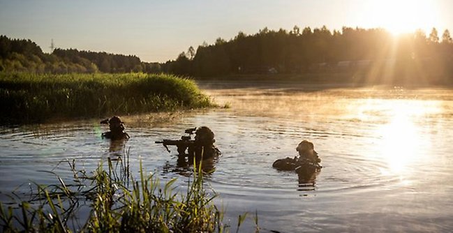 three soldiers walking in a lake with raised weaponsa