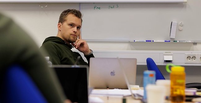 Manlig student som tänker vid whiteboard.