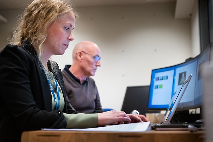 Two persons in front of computers.