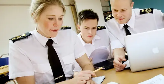 A group of people sitting at a table working on a laptop.