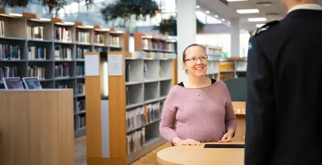 A woman standing in front of a man in a library.