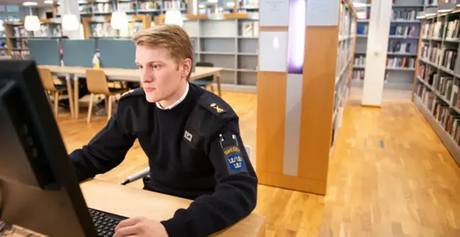 A man sitting at a computer in a library.