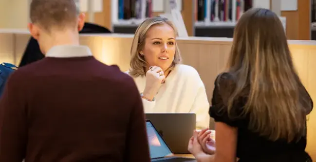A group of people sitting around a table with laptops.