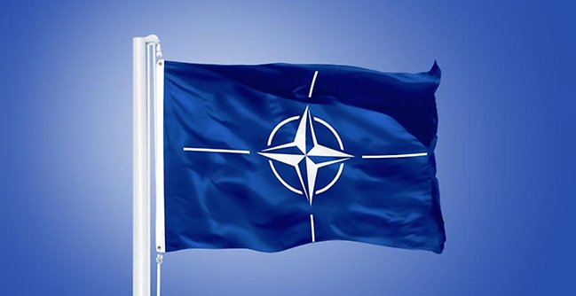 The NATO flag flying in the sky.