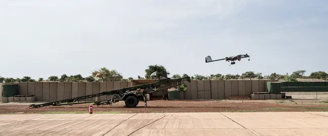 A drone is ejected over a dirt field..