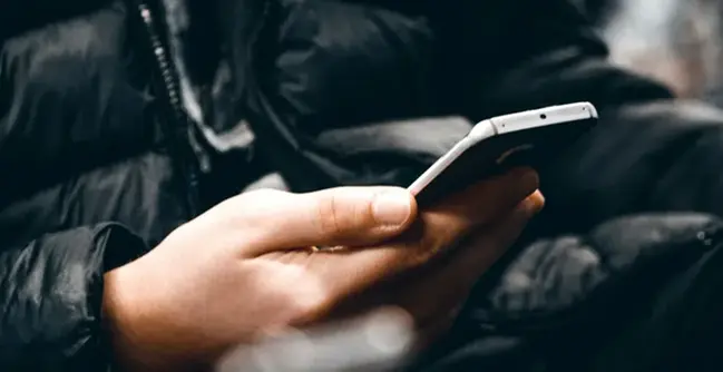 En person som håller en mobiltelefon i handen.