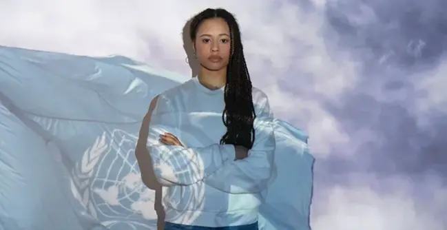 A woman in front of the UN flag.